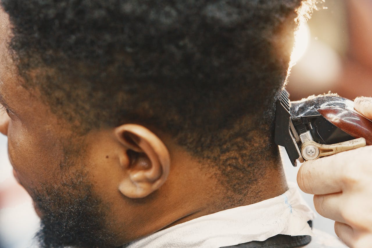 hero-img-01 Detailed view of a barber using clippers to trim a man's hair, capturing the essence of grooming.