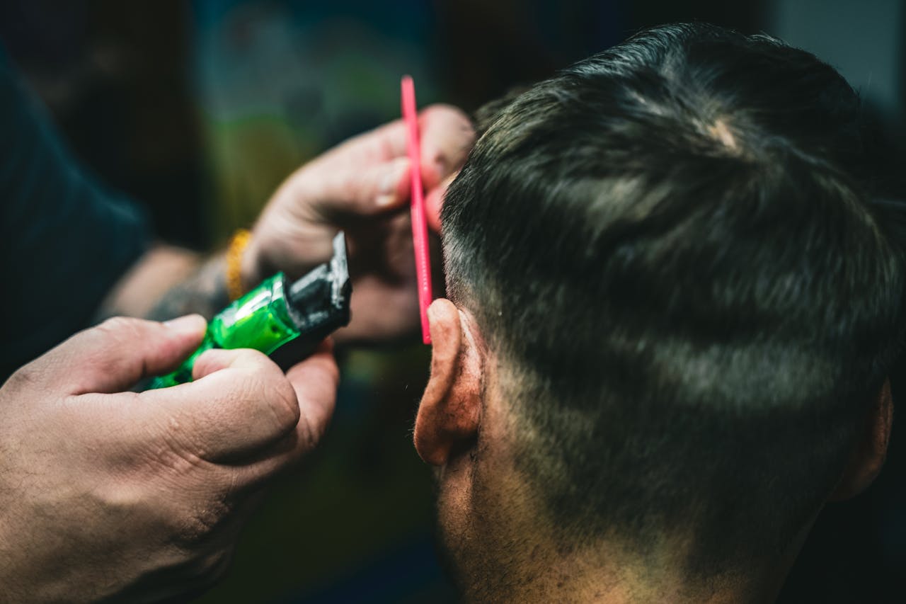 hero-img-02 A barber precisely cuts hair with a trimmer and comb, capturing a detailed grooming scene.